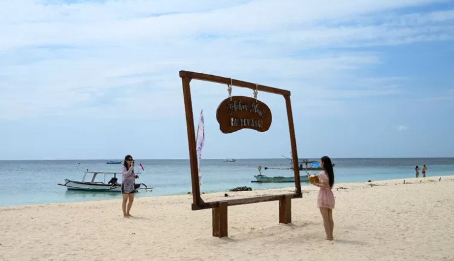 PUNYA DAYA TARIK: Rombongan wisatawan dari Tiongkok menikmati keindahan pantai Pulau Tabuhan yang memiliki pasir putih tersebut. (Ramada Kusuma/Radar Banyuwangi)/Ulanda.id
